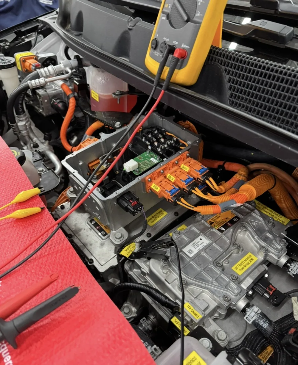 Meter and test leads beside exposed EV electronics during diagnostic work